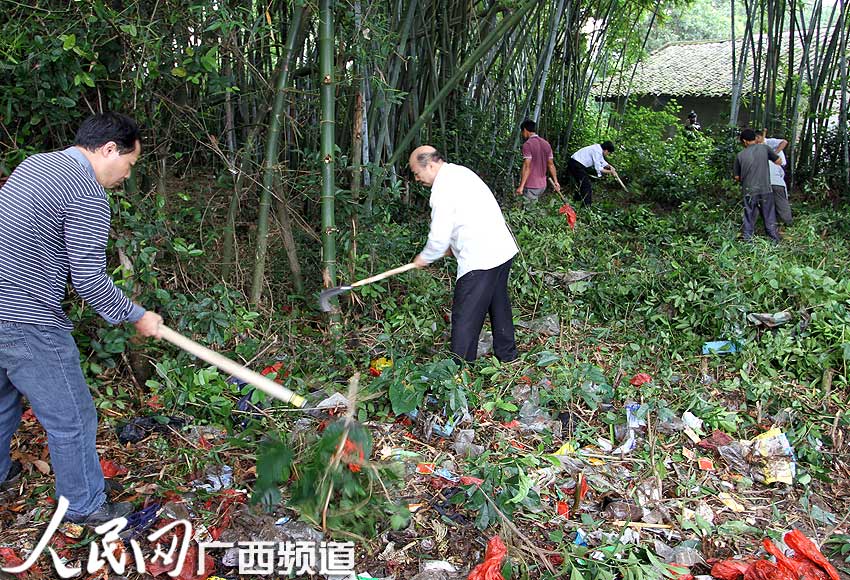 图为干部群众在温泉镇洞心村清理路边杂草,垃圾