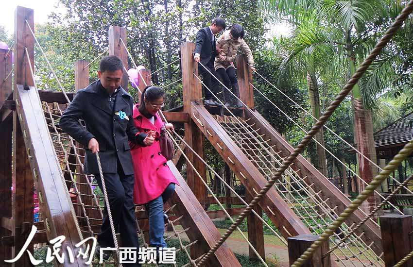 在名为“幸福彼岸”的游戏中,男女青年比赛攀爬绳 ...
