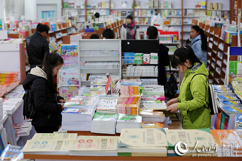 2月21日,在广西柳州市融安县新华书店,八年级学生温昕(右)和同学在