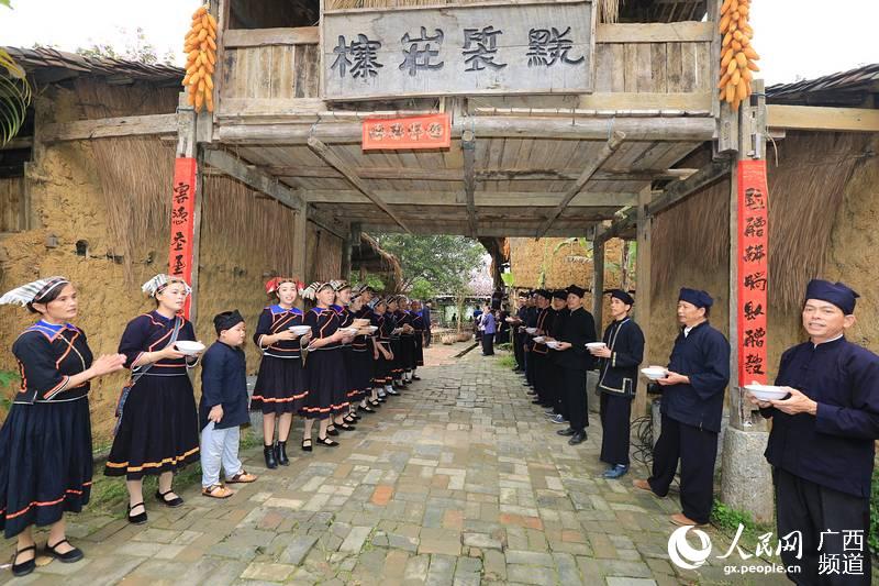 壮乡民居村寨，村民端着酒碗迎接客人的到来