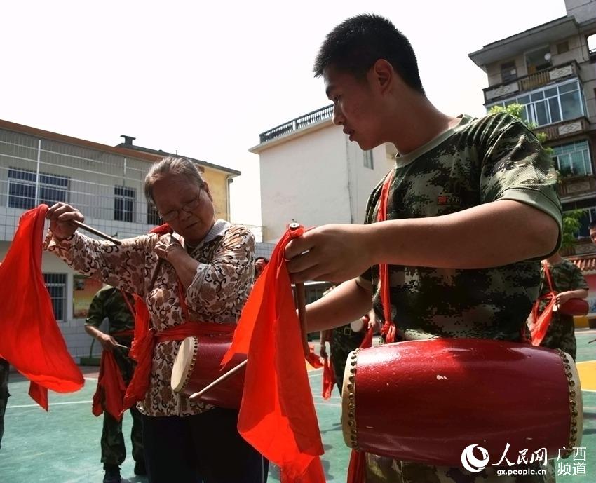 5月22日，广西南宁市隆安县夕阳红老年文艺队黄秀珍（左一）老师正在教武警战士腰鼓动作。