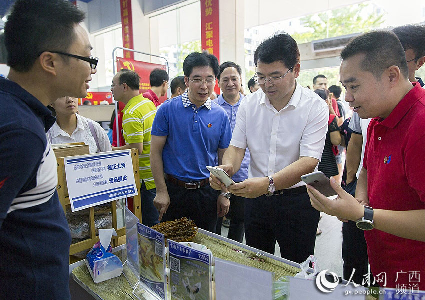 桂林市委常委,组织部部长李国忠(右二)在成果展现场用手机拍农产品