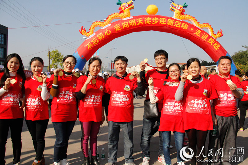 广西扶绥县干部群众在终点拱门前展示纪念奖牌