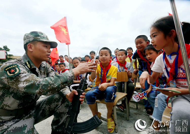 广西融安县人民武装部战士正在给孩子们传授枪械知识