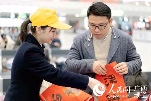 柳州站志願者為旅客送春聯。李俊鳴攝