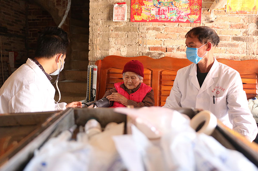 蒼梧縣京南鎮外旺村羅春華、羅宇強父子在為貧困戶測量血壓。廖偉攝