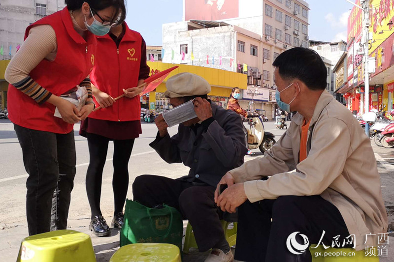 圖為志願者在街上指導群眾正確使用口罩。浦北縣委宣傳部供圖