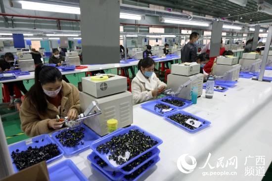 在廣西三江侗族自治縣聚米電子科技有限公司，人們在車間內加工零件。龔普康攝
