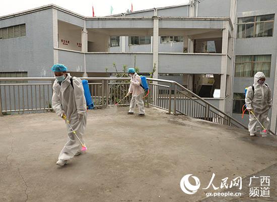 工作人員在使用消毒液對天峨中學校園公共區域進行消毒。田世遠攝