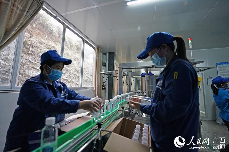 當地貧困戶正在一家食品有限公司裡邊包裝飲用水。韋吉陽攝