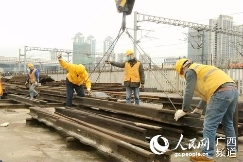 石才壯指導工友吊運鋼軌。覃文願攝