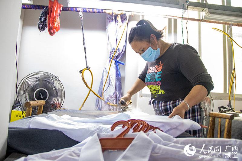 在位於賓陽縣賓州鎮的天才制衣廠就業扶貧車間內，工人正在熨燙成衣。吳明江攝
