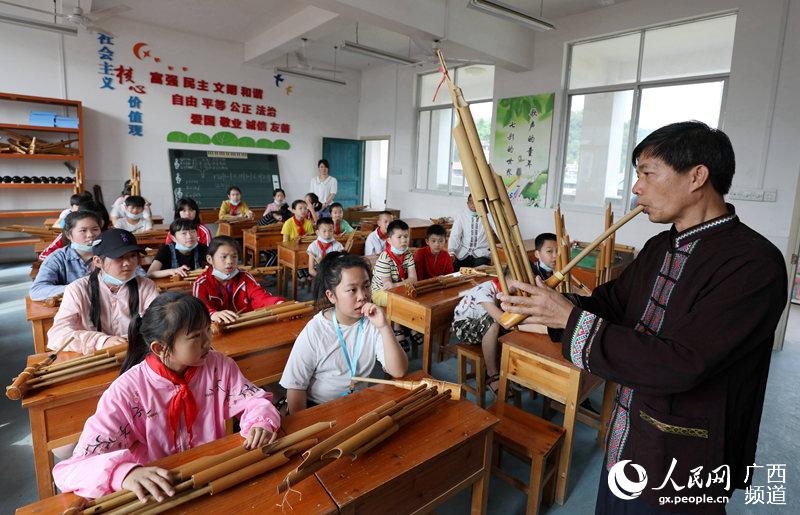 5月13日，一名文化館老師在三江侗族自治縣古宜鎮中心小學教學生吹蘆笙。龔普康攝