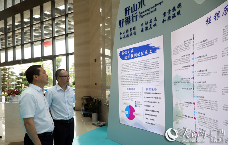 吳東（右一）陪同彭代元參觀桂林銀行企業文化展廳。蔣琛攝