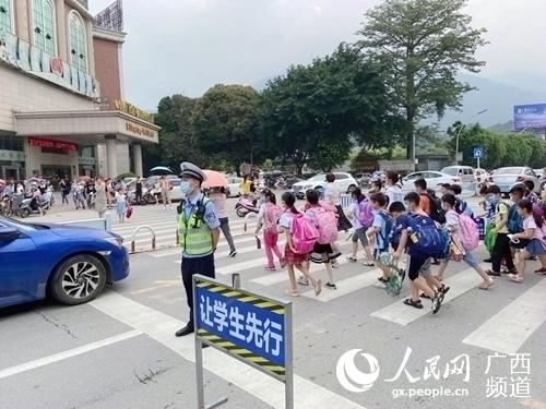圖為桂平交警引導學生安全通過馬路。桂平市公安局交警大隊供圖