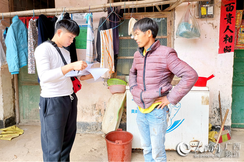 圖為吳東鴻（左一）正在筆記本上記錄著貧困戶的每一筆產業賬。馮堅業攝