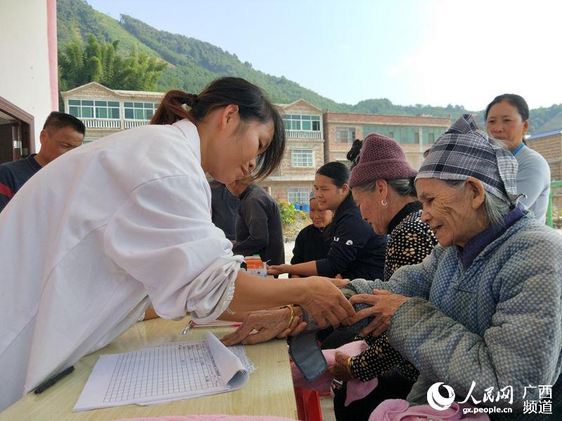 圖為田林縣八桂瑤族鄉弄瓦衛生院護士韋海英在免費幫當地建檔立卡貧困戶黃迷文測血壓。楊進宏攝