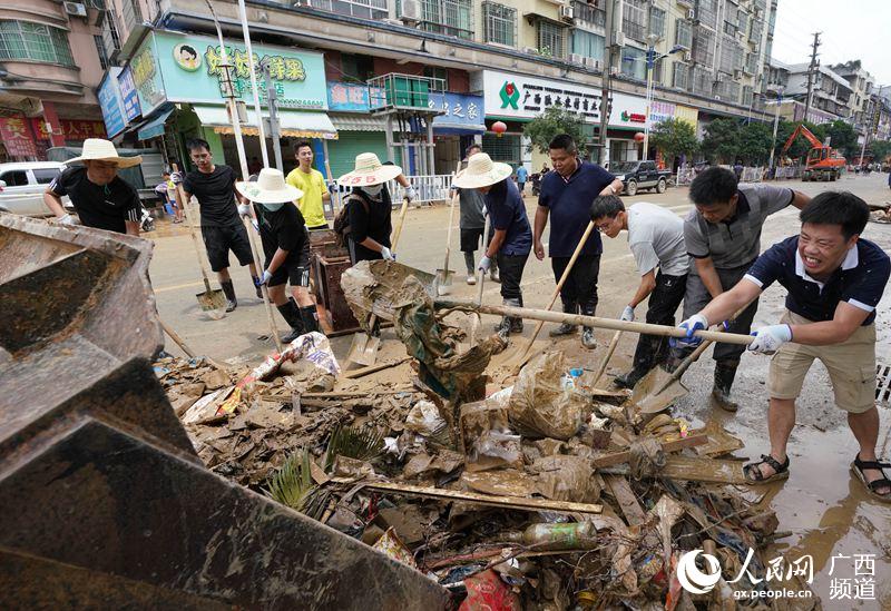 7月12日，該縣紀檢監察干部與黨員志願者將垃圾鏟上推土機。龍林智攝
