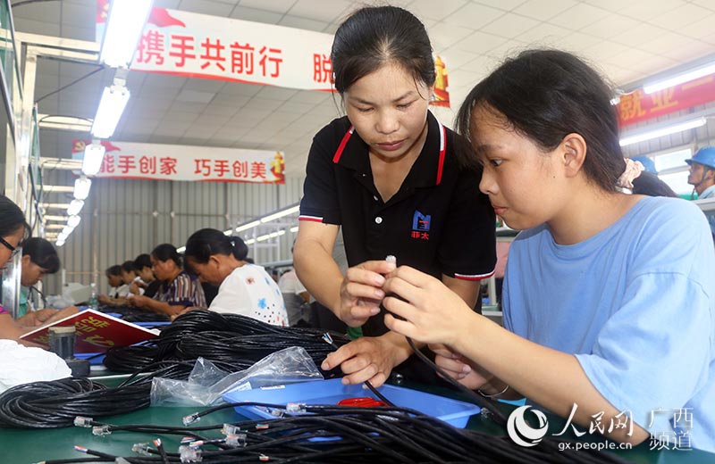 賀州菲太電子有限公司技術人員在雙元村扶貧車間指導工人工作。廖超文攝