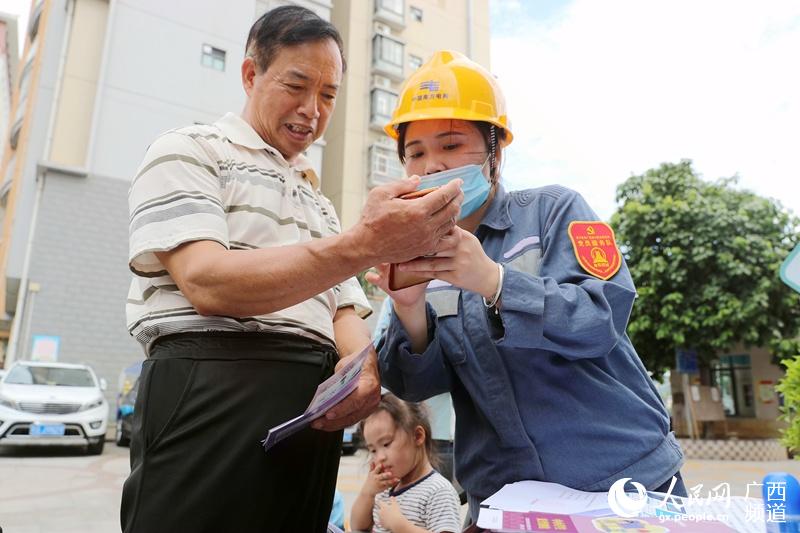南寧供電局工作人員現場為客戶操作手機辦理電價優惠。黃任任攝