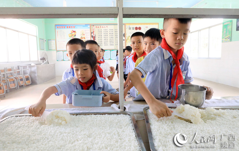 學生們正在盛米飯。譚凱興攝