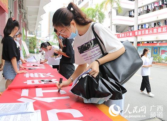 学生在“节粮”宣传横幅上签名。雷秀燕摄
