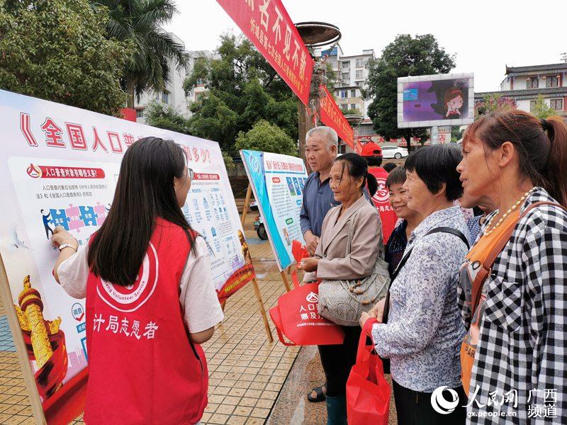 忻城縣統計局工作人員站在展板前向群眾介紹人口普查知識。黃世歷攝