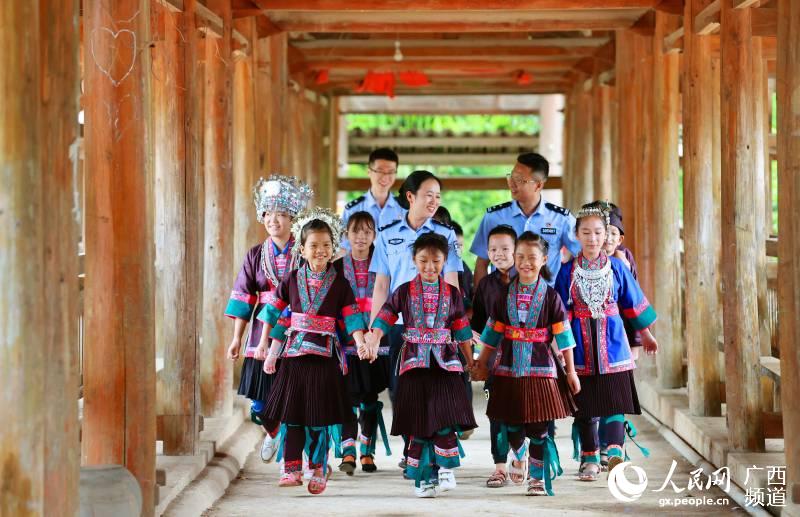 惠州邊檢站扶貧民警與侗族學童在風雨橋上手牽手唱童謠。廖鍵攝