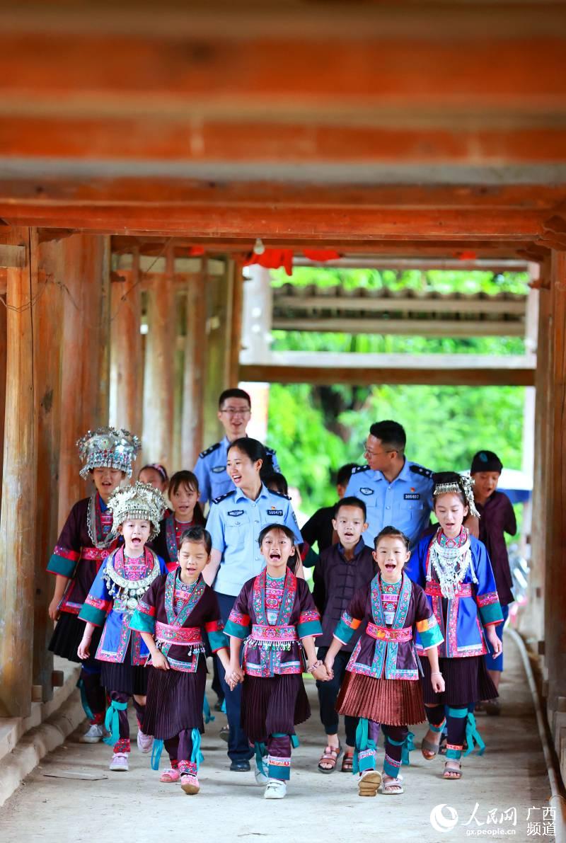 惠州邊檢站扶貧民警與侗族學童在風雨橋上手牽手唱童謠。廖鍵攝