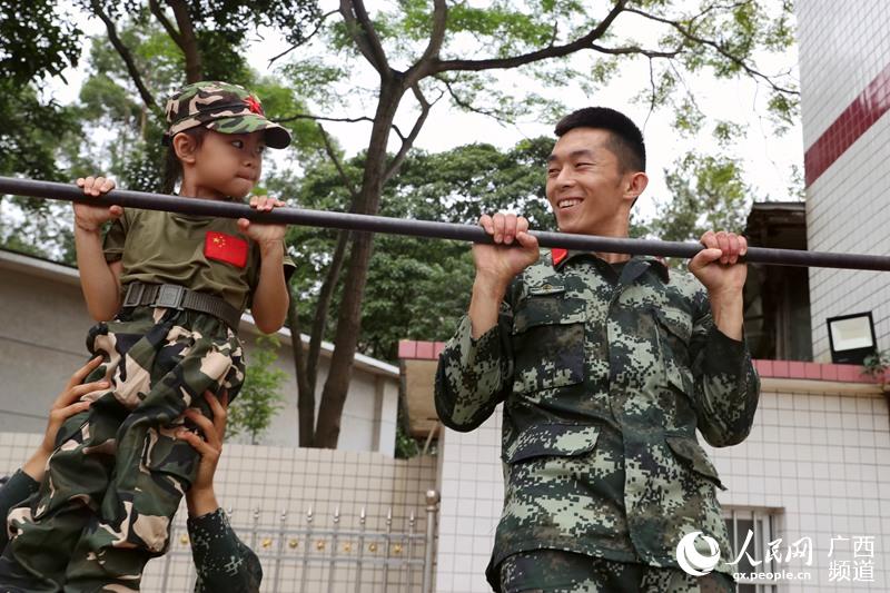 “萌娃”和兵哥哥一起體驗單杠。武警南寧支隊供圖