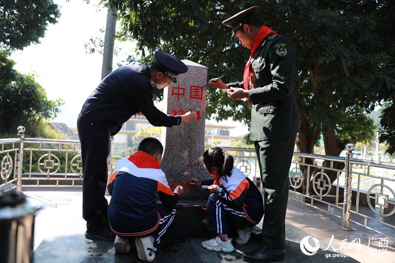 12月9日，少先隊員與官兵代表走邊境線，護理界碑，為界碑描紅。寧明縣委宣傳部供圖