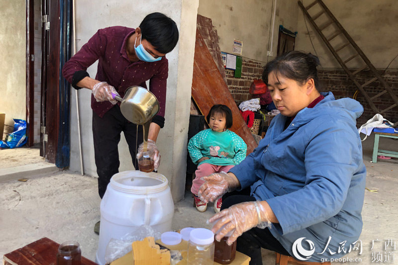 陸蒙和妻子將蜂蜜倒入罐子。鹿寨縣融媒體中心供圖