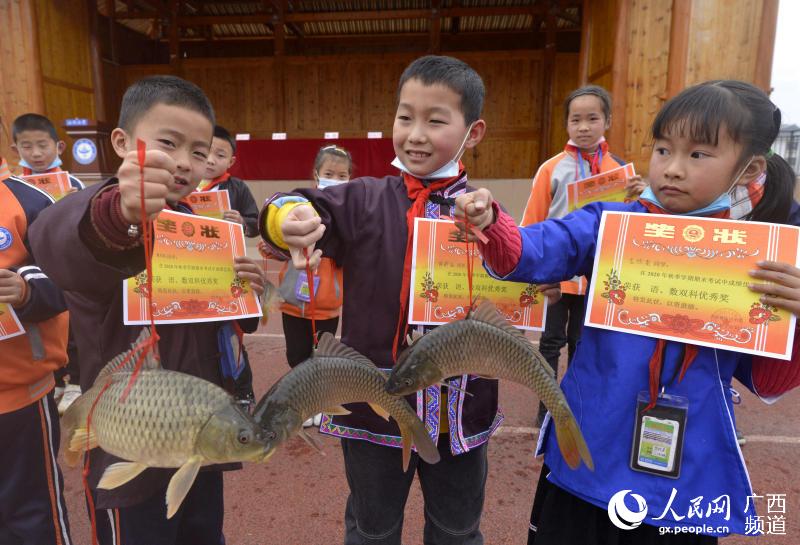 圖為孩子們展示魚和獎狀。滾億忠攝