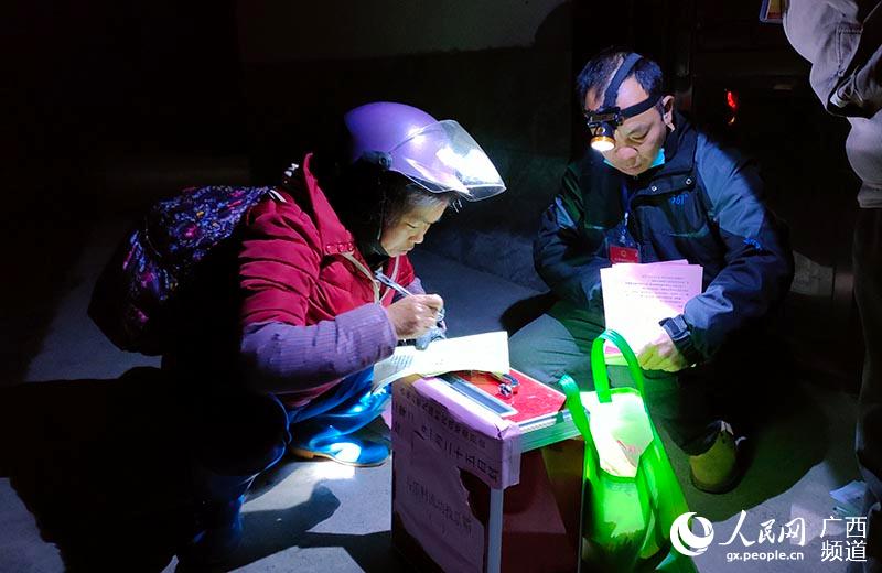 普益鄉早起務工村民在電筒光下填寫選票。陽朔縣委組織部供圖