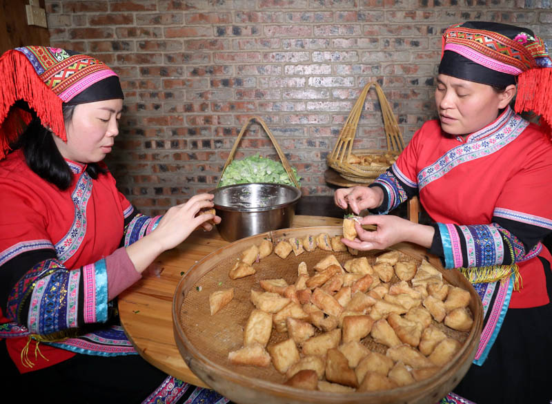 兩名婦女在給三角豆腐果填充肉餡。龔普康攝