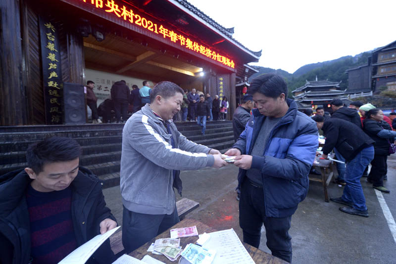 圖為村民接過分紅。滾億忠攝