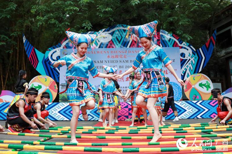 在廣西桂平市西山風景名勝區，身著民族服飾的青年跳起竹竿舞，歡慶壯鄉歌節。人民網 吳明江攝