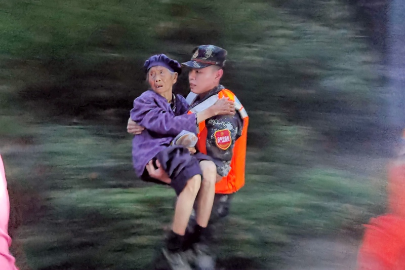 武警官兵抱起行動不便的老人進行安全轉移。
