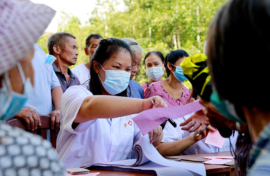杨小燕为准备接种疫苗的村民填写信息。