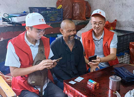 中國電信志願者在指導黃爹爹使用5G手機。白文彬攝