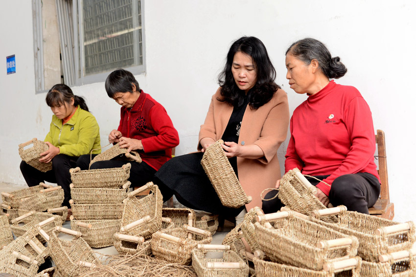 人大代表梁志巧（右二）给村民传授编织技艺。
