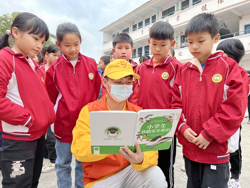 青年志願者在給小學生講解鐵路春運安全知識和人身安全保護條款。鄭宇彤攝