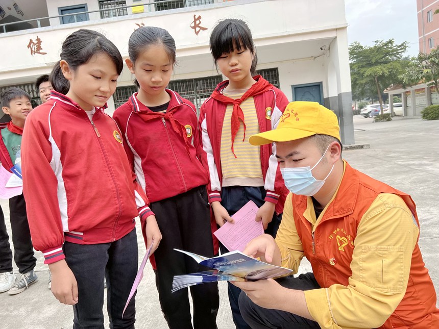 青年志願者在給小學生詳細講解鐵路春運安全知識和人身安全保護條款。鄭宇彤攝