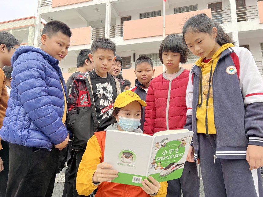 青年志願者在給小學生講解學習鐵路春運安全知識和人身安全保護條款。鄭宇彤攝