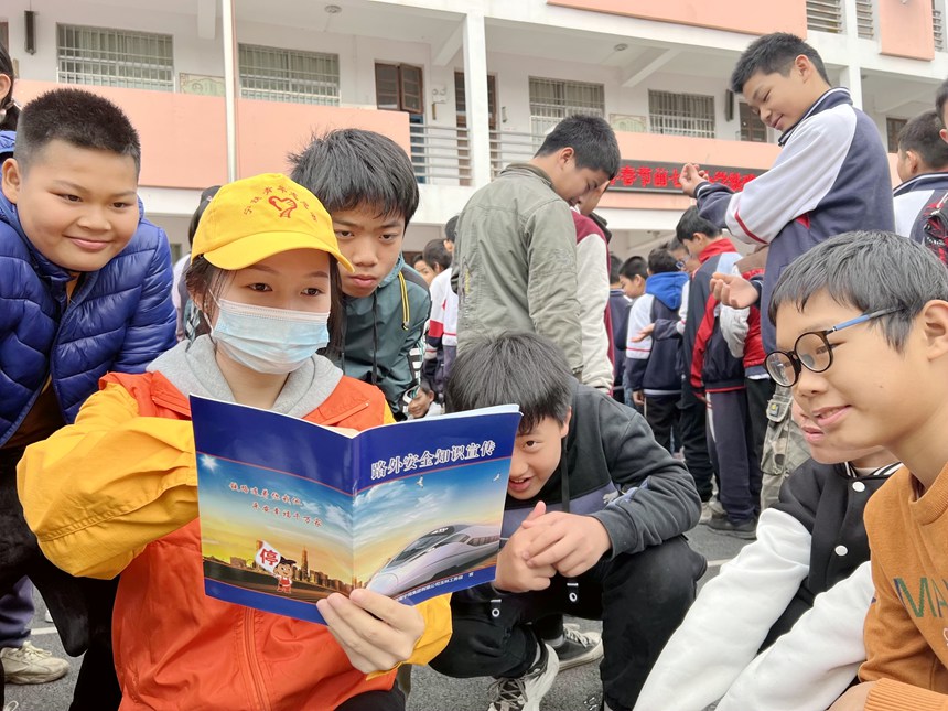青年志願者在給小學生認真講解鐵路春運安全知識和人身安全保護條款。鄭宇彤攝