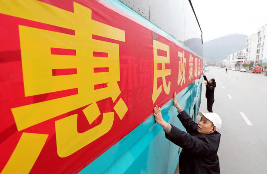 在融安县粤桂劳务合作工作站，工作人员在返岗专车上张贴标语。