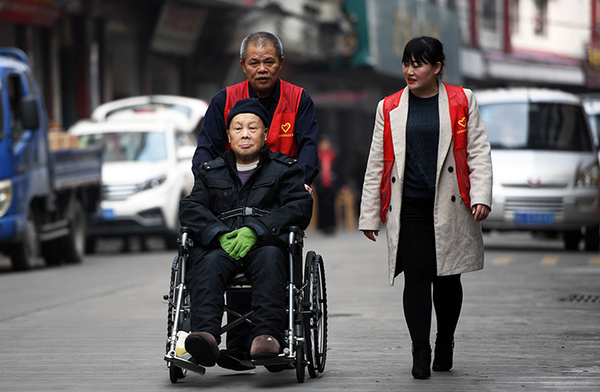 3月4日，在广西龙胜各族自治县龙胜镇城南社区，志愿者用轮椅带老人上街散心。