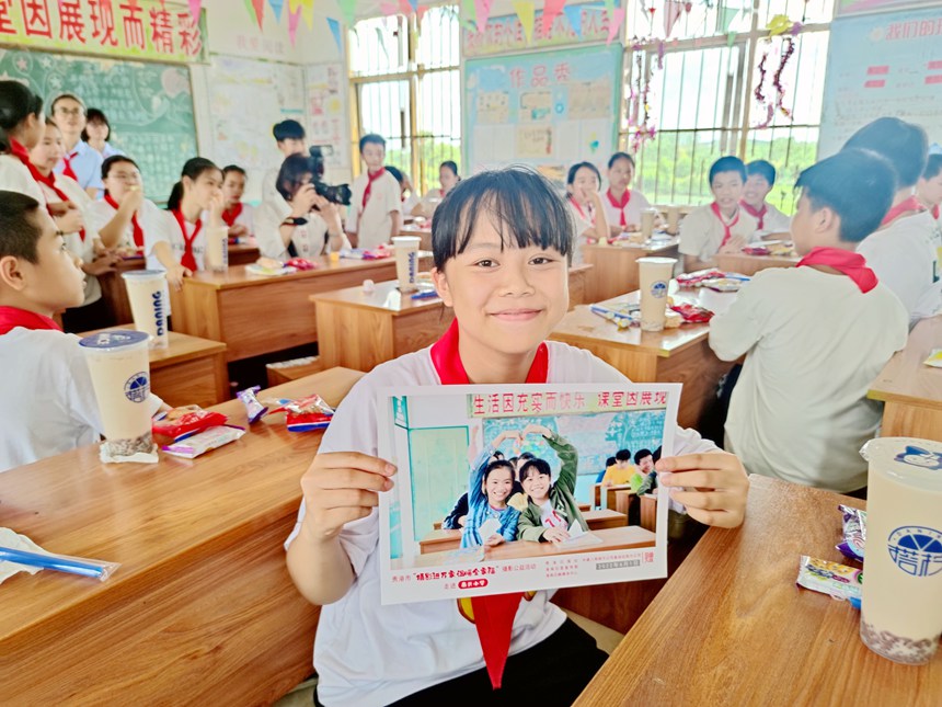 一名女生在展示刚拿到的和同桌的合照。
