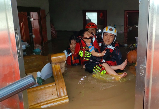 6月19日消防救援人员何刚在全州县枧塘镇兴隆村转移两名被困留守儿童。桂林市消防支队供图