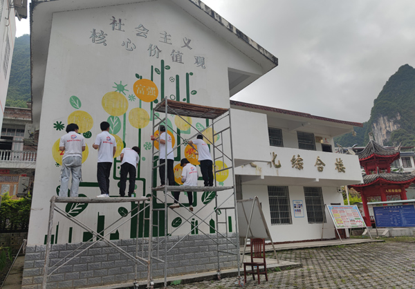 广西科技师范学院美术与设计学院学生运用专业技能为忻城县六纳村文化综合楼墙绘翻新。莫文华摄